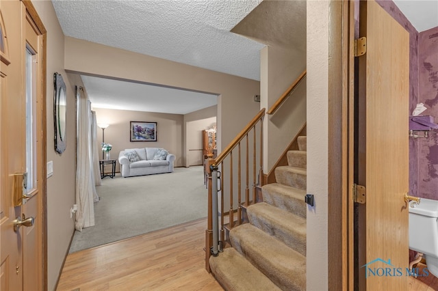 stairway featuring wood-type flooring and a textured ceiling