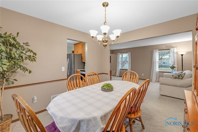 dining area with light carpet and a chandelier