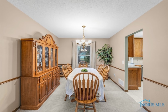 dining room with light colored carpet, a textured ceiling, and a chandelier