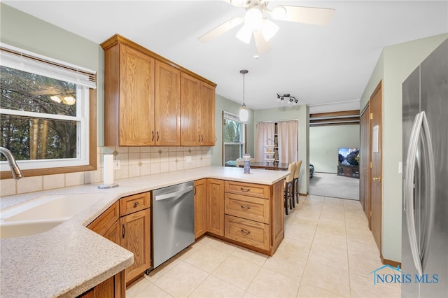 kitchen featuring sink, hanging light fixtures, kitchen peninsula, stainless steel appliances, and decorative backsplash