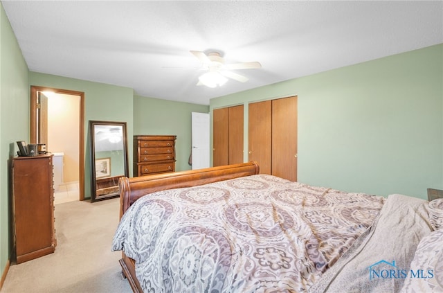 bedroom with two closets, light colored carpet, and ceiling fan