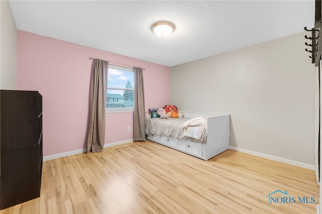 bedroom featuring a textured ceiling and light wood-type flooring