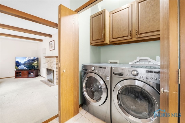 laundry room featuring washer and dryer, a fireplace, cabinets, and light tile patterned flooring