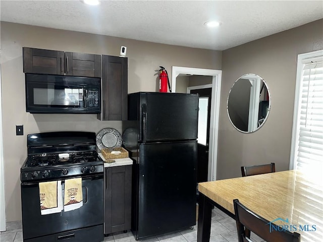 kitchen with light tile patterned flooring, a textured ceiling, and black appliances