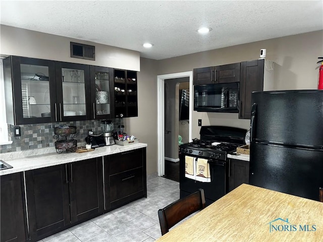 kitchen with backsplash, light tile patterned floors, a textured ceiling, and black appliances