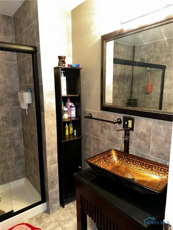 bathroom featuring tile walls, sink, tile patterned floors, and a shower with door