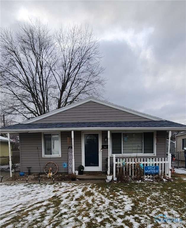 view of front of property featuring roof with shingles and fence