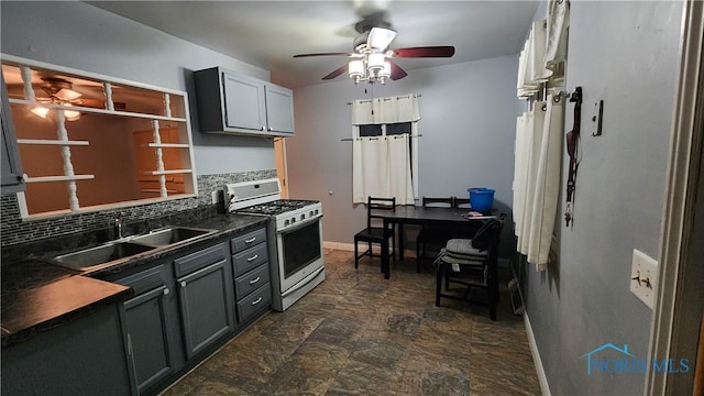 kitchen featuring gas range gas stove, tasteful backsplash, dark countertops, gray cabinetry, and a sink