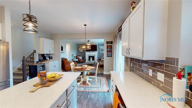 kitchen with white cabinetry, dark hardwood / wood-style flooring, light stone counters, and hanging light fixtures