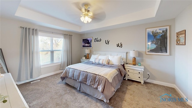 bedroom with a tray ceiling, light colored carpet, and ceiling fan