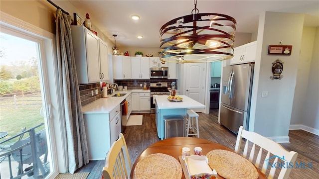 kitchen with stainless steel appliances, a center island, white cabinets, and decorative light fixtures