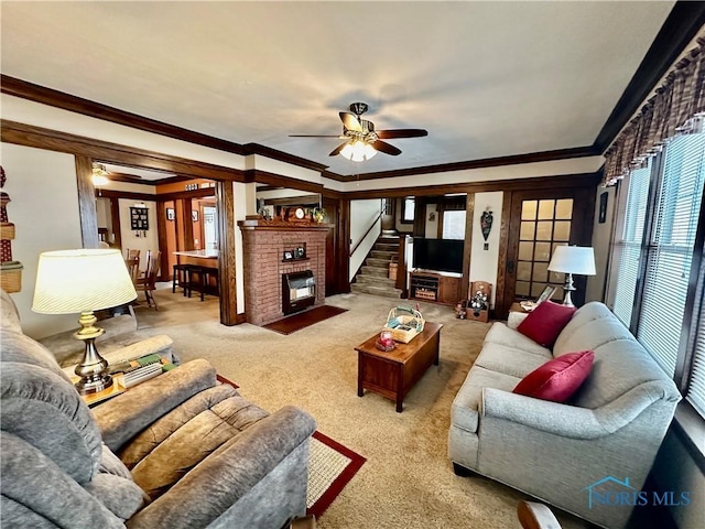 living room with ceiling fan, crown molding, light colored carpet, and a fireplace