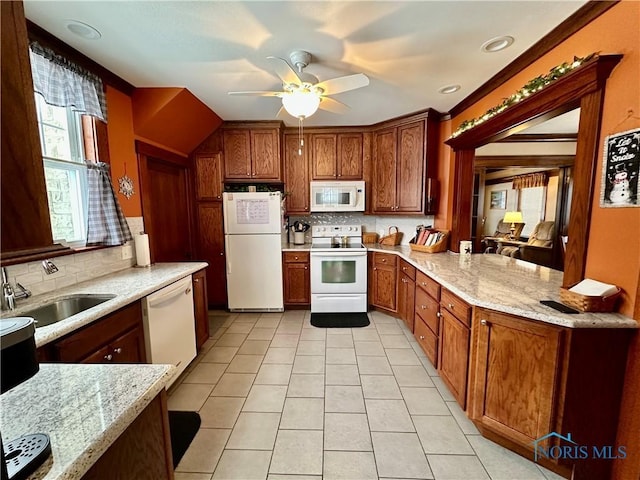 kitchen featuring white appliances, light stone countertops, sink, and decorative backsplash