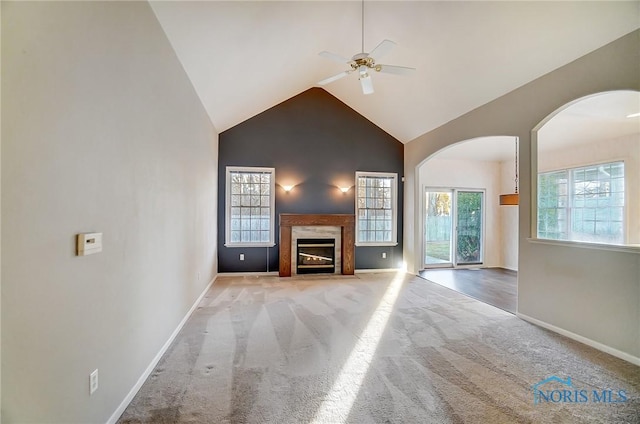 unfurnished living room featuring high vaulted ceiling, a premium fireplace, ceiling fan, and carpet flooring