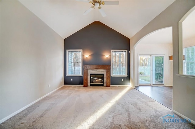 unfurnished living room with a premium fireplace, vaulted ceiling, a healthy amount of sunlight, and light colored carpet