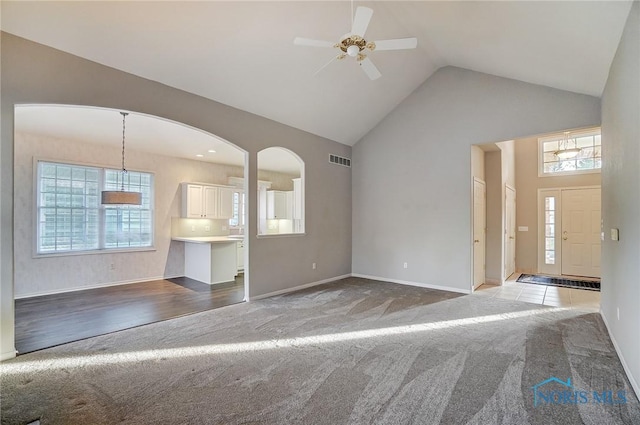 unfurnished living room featuring ceiling fan, light colored carpet, and high vaulted ceiling