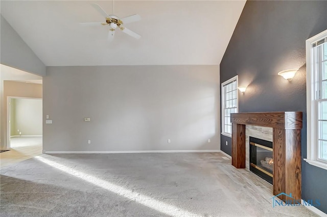 unfurnished living room featuring lofted ceiling, light colored carpet, ceiling fan, a healthy amount of sunlight, and a premium fireplace