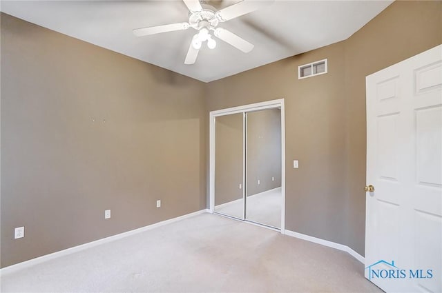 unfurnished bedroom with light colored carpet, a closet, and ceiling fan