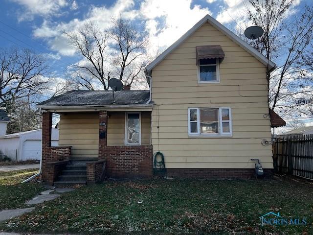 back of house featuring fence, a lawn, and brick siding