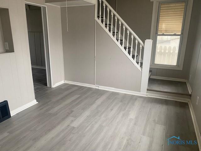 empty room with baseboards, attic access, stairway, and wood finished floors