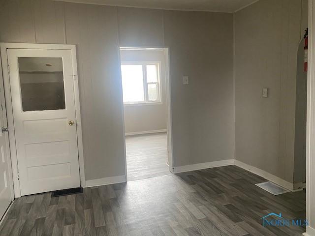 unfurnished room featuring dark wood-style floors, arched walkways, and baseboards