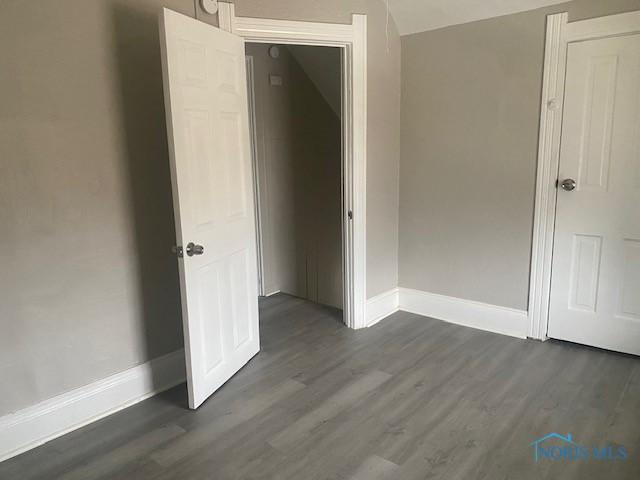 unfurnished bedroom featuring dark wood finished floors and baseboards