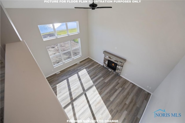 unfurnished living room featuring dark hardwood / wood-style flooring, a fireplace, ceiling fan, and a high ceiling