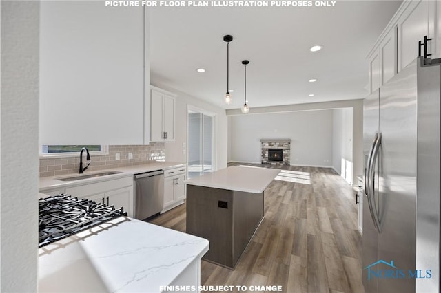 kitchen with appliances with stainless steel finishes, pendant lighting, sink, white cabinets, and a center island