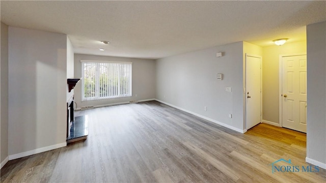 unfurnished living room with light hardwood / wood-style floors and a textured ceiling