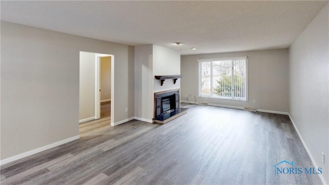 unfurnished living room featuring a textured ceiling and light wood-type flooring