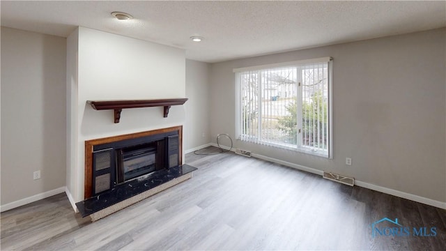 unfurnished living room featuring hardwood / wood-style floors and a textured ceiling