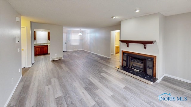 unfurnished living room with wood-type flooring and sink