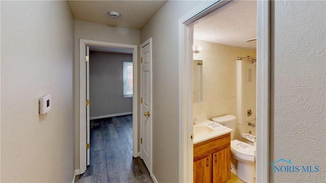 corridor with dark wood-type flooring and a textured ceiling