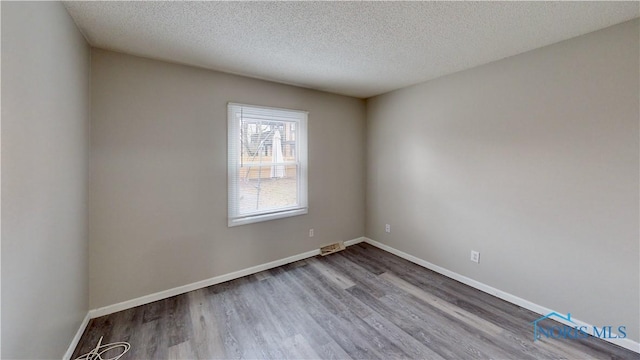 empty room featuring hardwood / wood-style flooring and a textured ceiling