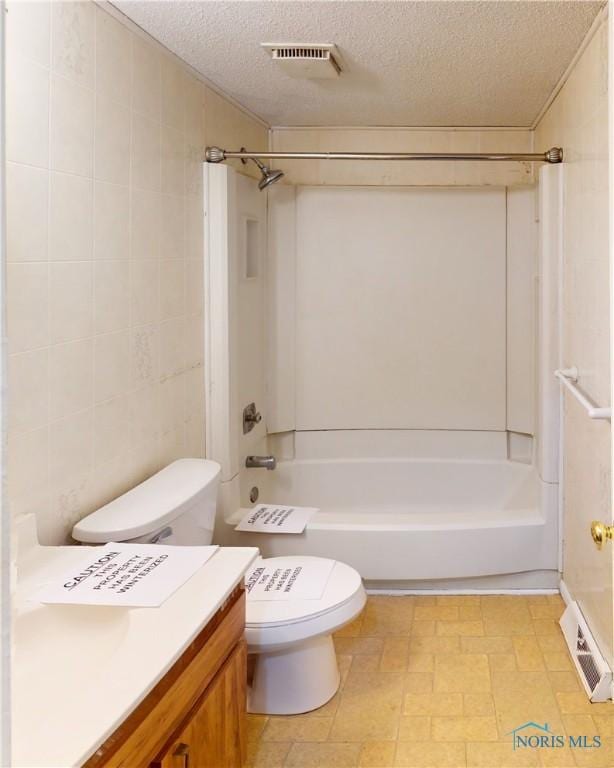 full bathroom with vanity,  shower combination, tile walls, and a textured ceiling