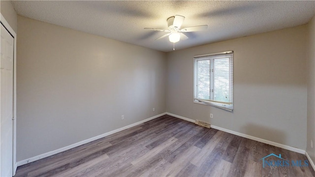 unfurnished room with ceiling fan, wood-type flooring, and a textured ceiling