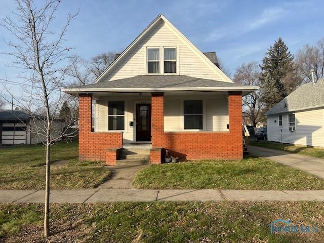 bungalow-style home with covered porch and a front lawn