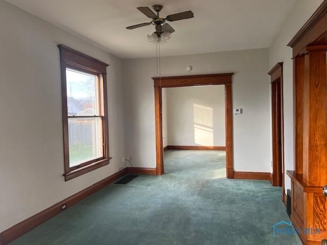 carpeted spare room with ceiling fan and plenty of natural light