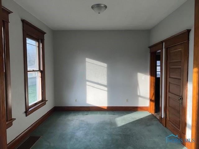 unfurnished room featuring dark colored carpet and plenty of natural light