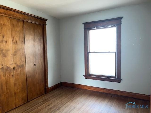 unfurnished bedroom featuring wood-type flooring and a closet