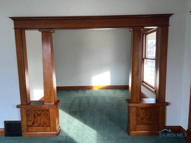 interior space featuring ornate columns and dark colored carpet