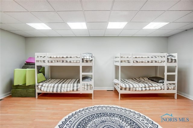 bedroom with a paneled ceiling and wood-type flooring