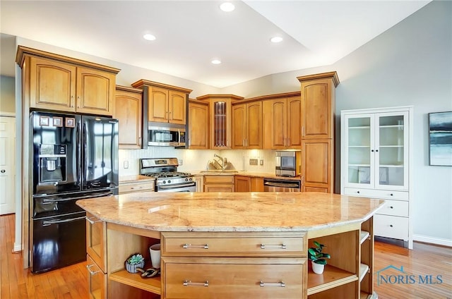 kitchen featuring appliances with stainless steel finishes, a center island, light hardwood / wood-style floors, and light stone countertops