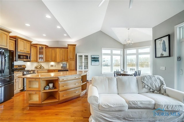 kitchen featuring decorative light fixtures, a center island, vaulted ceiling, stainless steel appliances, and light hardwood / wood-style floors