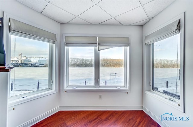 unfurnished room with hardwood / wood-style flooring, a water view, and a paneled ceiling