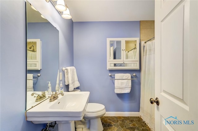 bathroom featuring sink, a shower with shower curtain, and toilet