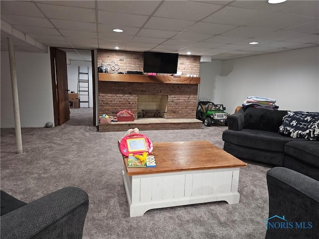 living room with a paneled ceiling, brick wall, carpet flooring, and a fireplace