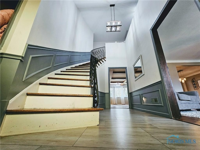 stairs with an inviting chandelier, hardwood / wood-style flooring, and a high ceiling