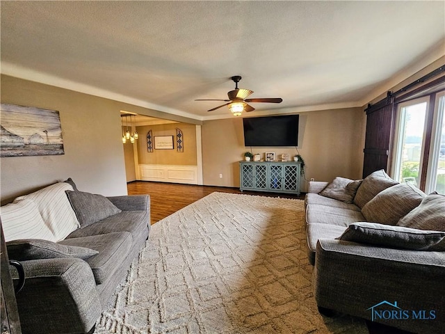 living room with ceiling fan with notable chandelier, hardwood / wood-style floors, and a textured ceiling