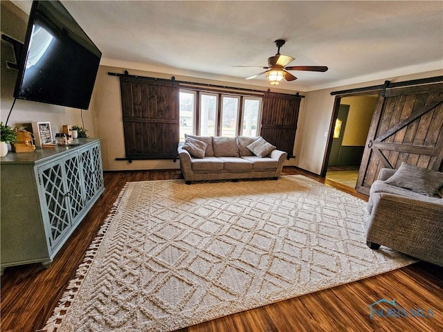 living room featuring hardwood / wood-style floors, a barn door, and ceiling fan